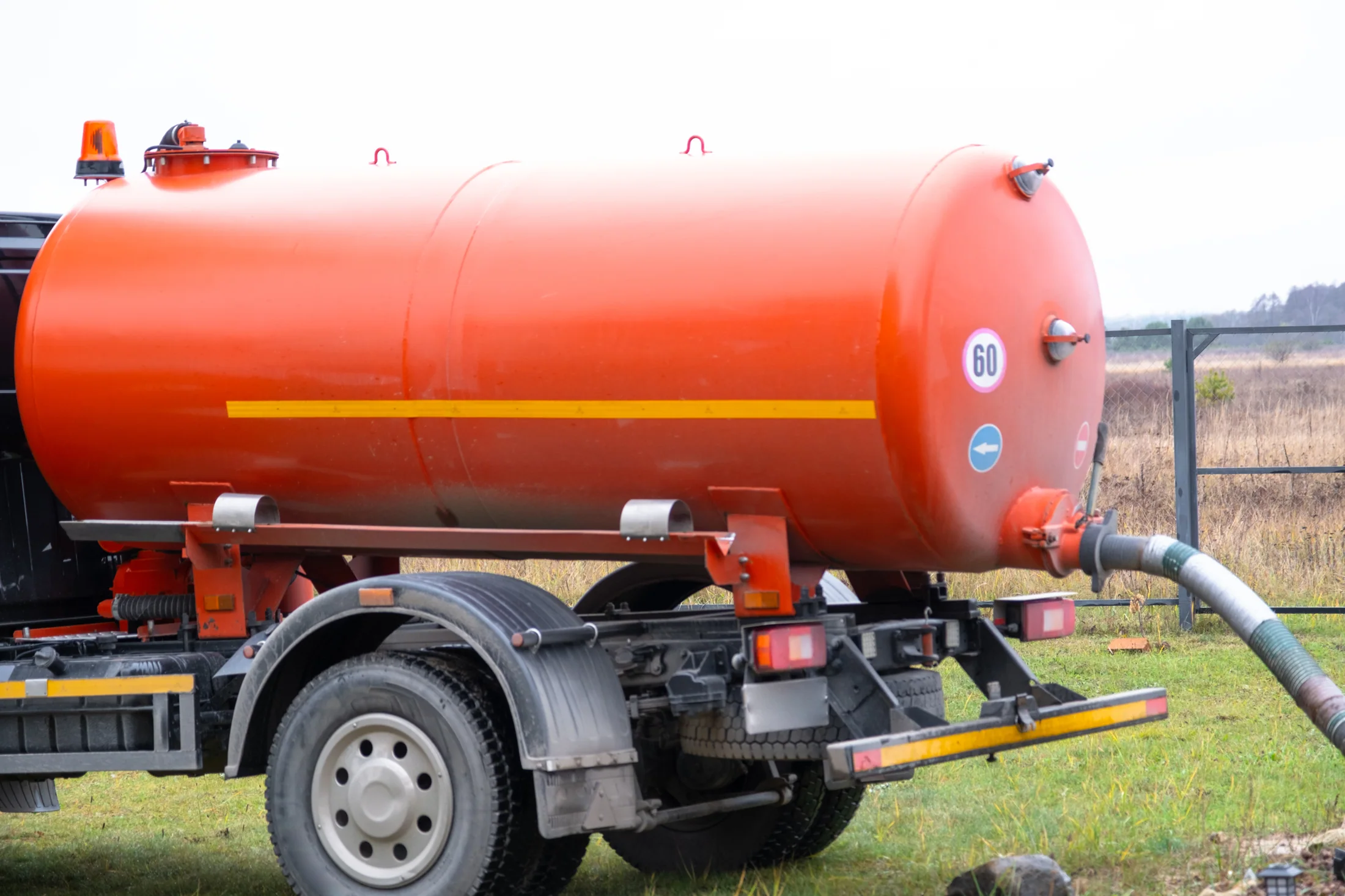 Rear of a vacuum tanker with a connected suction hose.