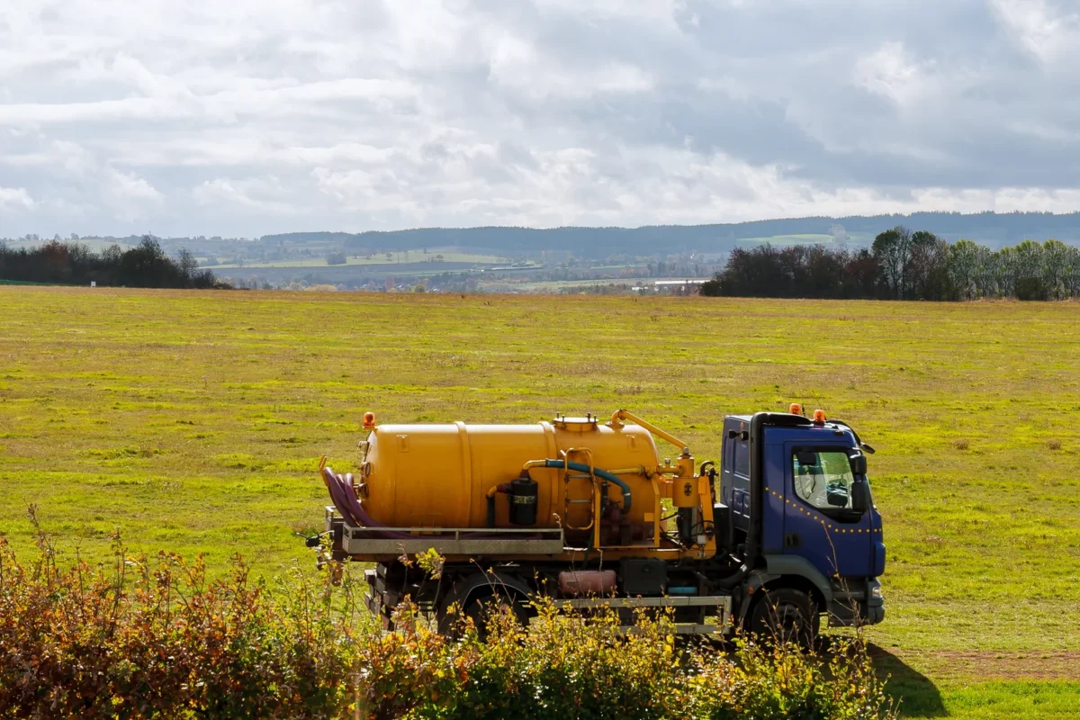 Yellow vacuum tanker beside an open rural field